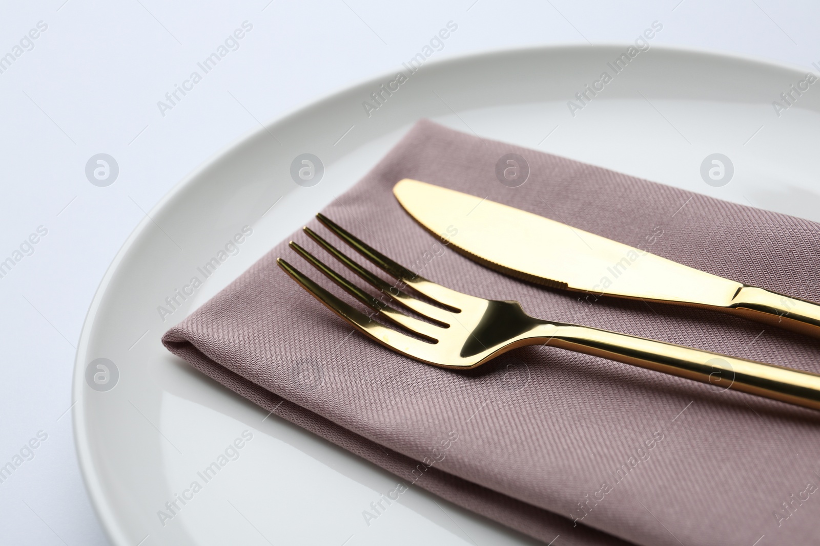 Photo of Stylish elegant cutlery with napkin in plate on white background, closeup