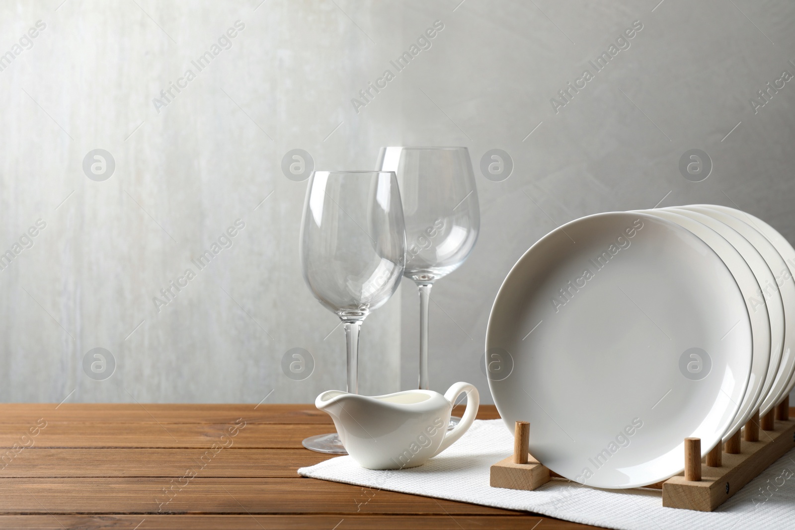 Photo of Set of clean dishware and glasses on wooden table, space for text