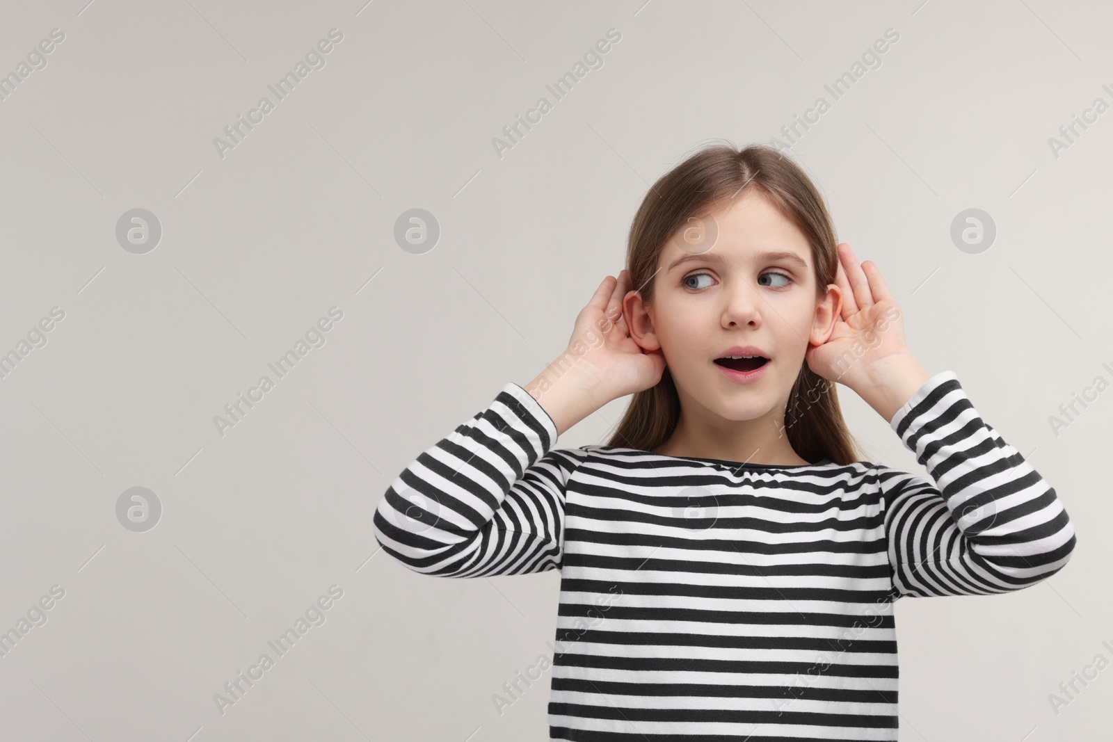 Photo of Little girl with hearing problem on grey background, space for text