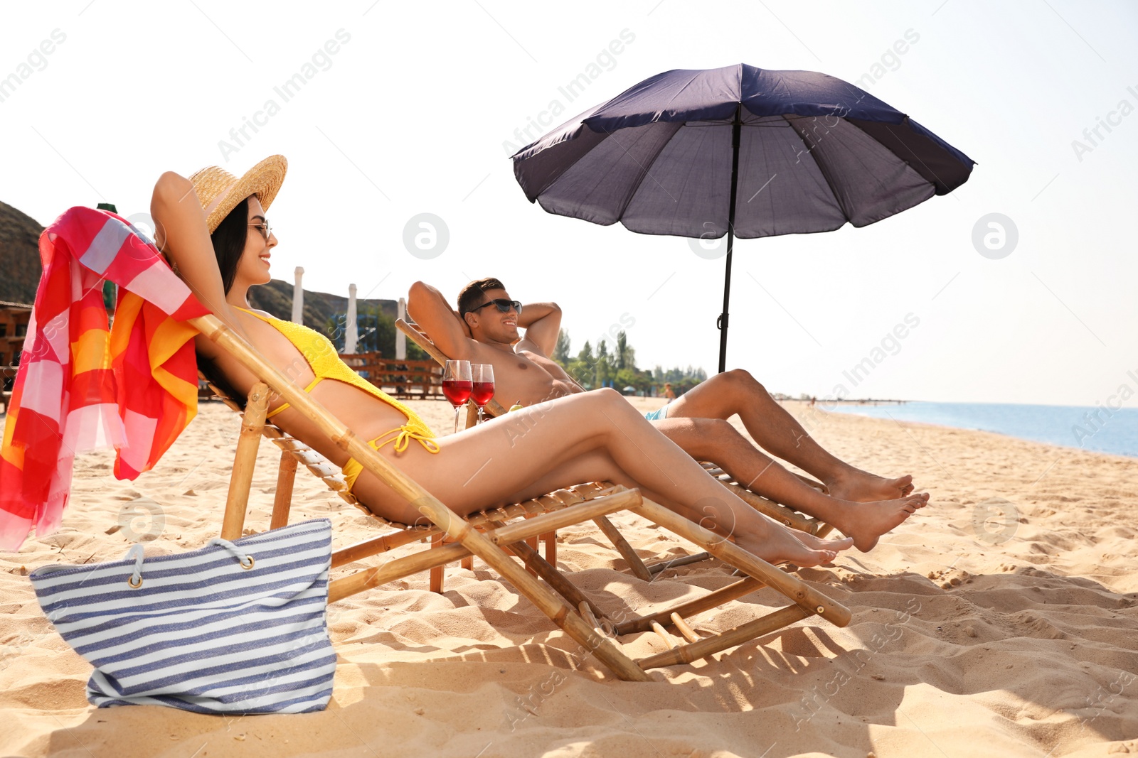 Photo of Happy couple resting on sunny beach at resort