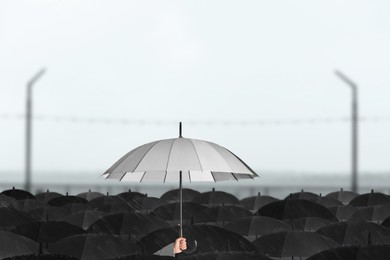 Person holding umbrella over other under heavy rain outdoors 