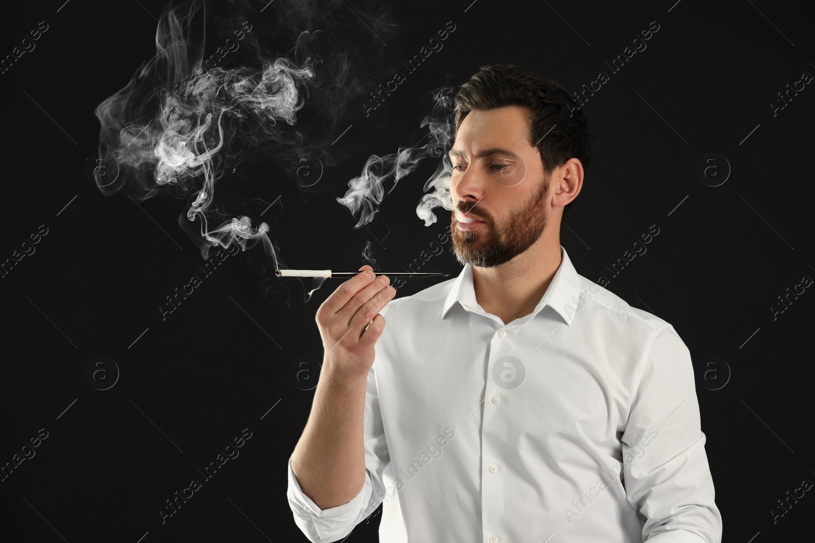 Photo of Man using long cigarette holder for smoking on black background