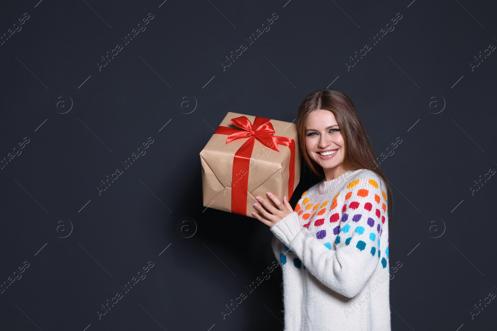 Photo of Young woman with Christmas gift on dark background. Space for text