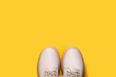 Photo of Pair of stylish leather shoes on yellow background, flat lay. Space for text