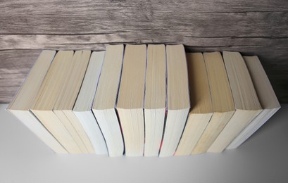 Photo of Collection of different books on white shelf, above view