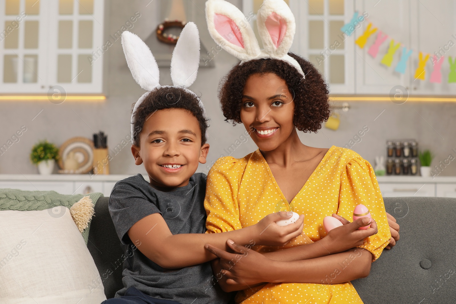 Photo of Happy African American mother and her cute son with Easter eggs indoors