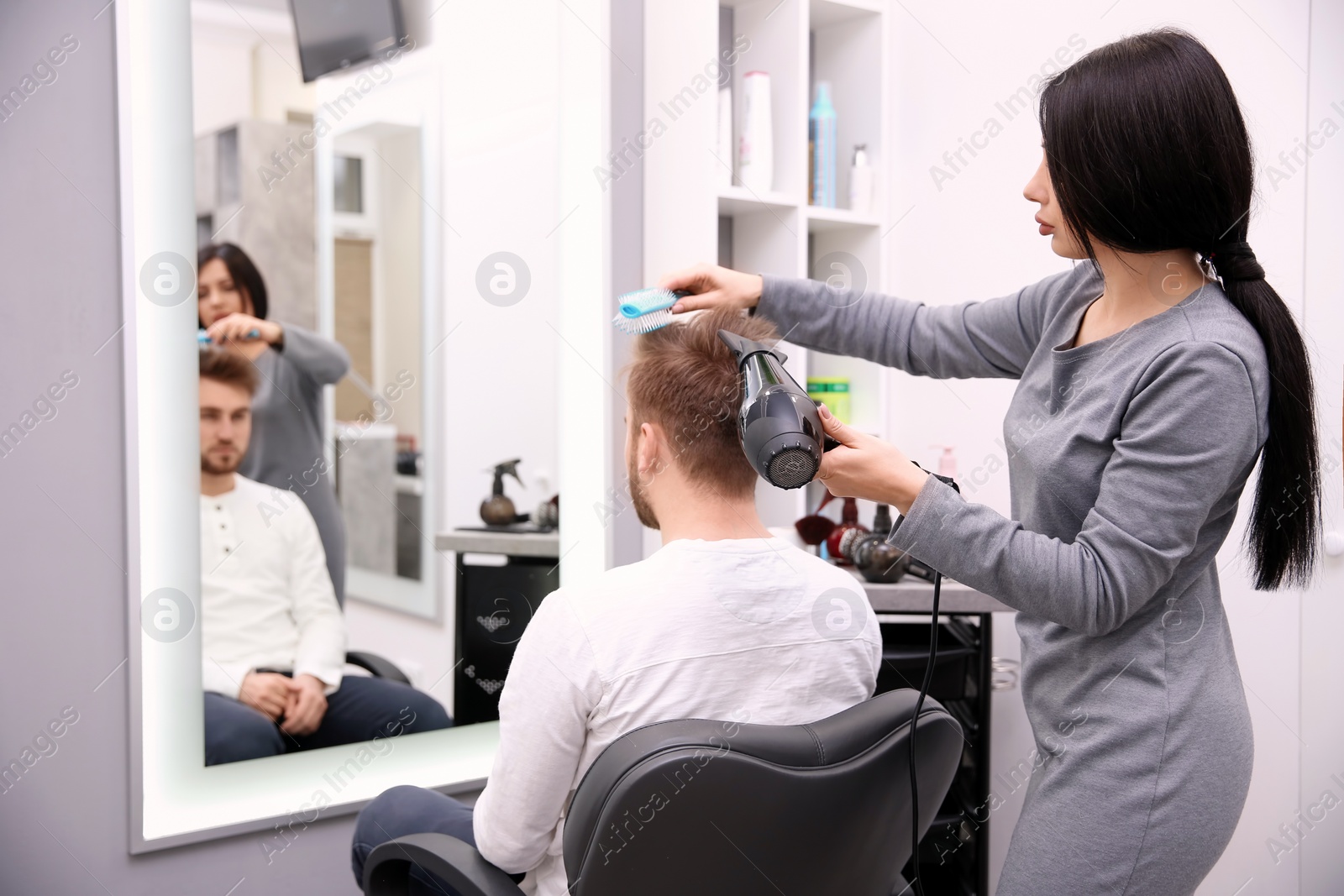 Photo of Professional female hairdresser working with client in salon