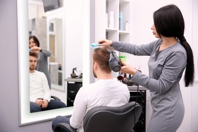 Photo of Professional female hairdresser working with client in salon