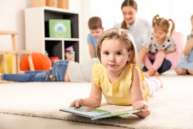 Photo of Cute little child with book indoors, space for text. Learning and playing