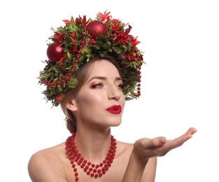 Photo of Beautiful young woman with Christmas wreath blowing kiss on white background