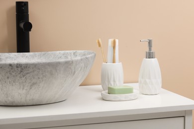 Photo of Different bath accessories and personal care products near sink on bathroom vanity