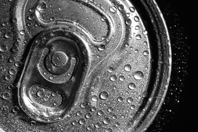 Photo of Aluminum can of beverage covered with water drops on black background, top view