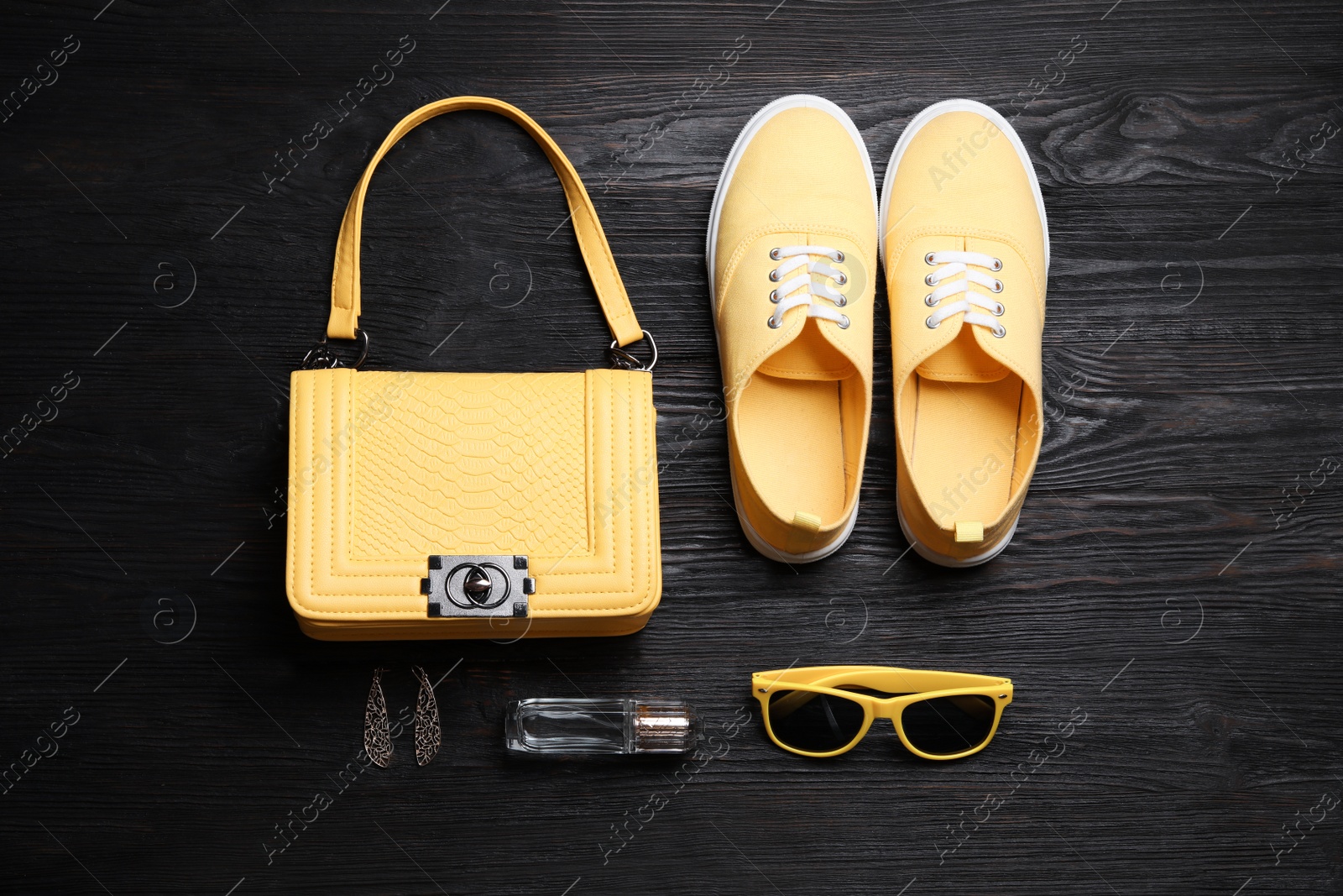 Photo of Stylish shoes, small woman's bag and accessories on black wooden table, flat lay