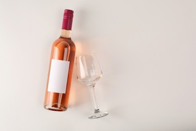 Photo of Bottle of tasty rose wine and glass on white background, flat lay. Space for text