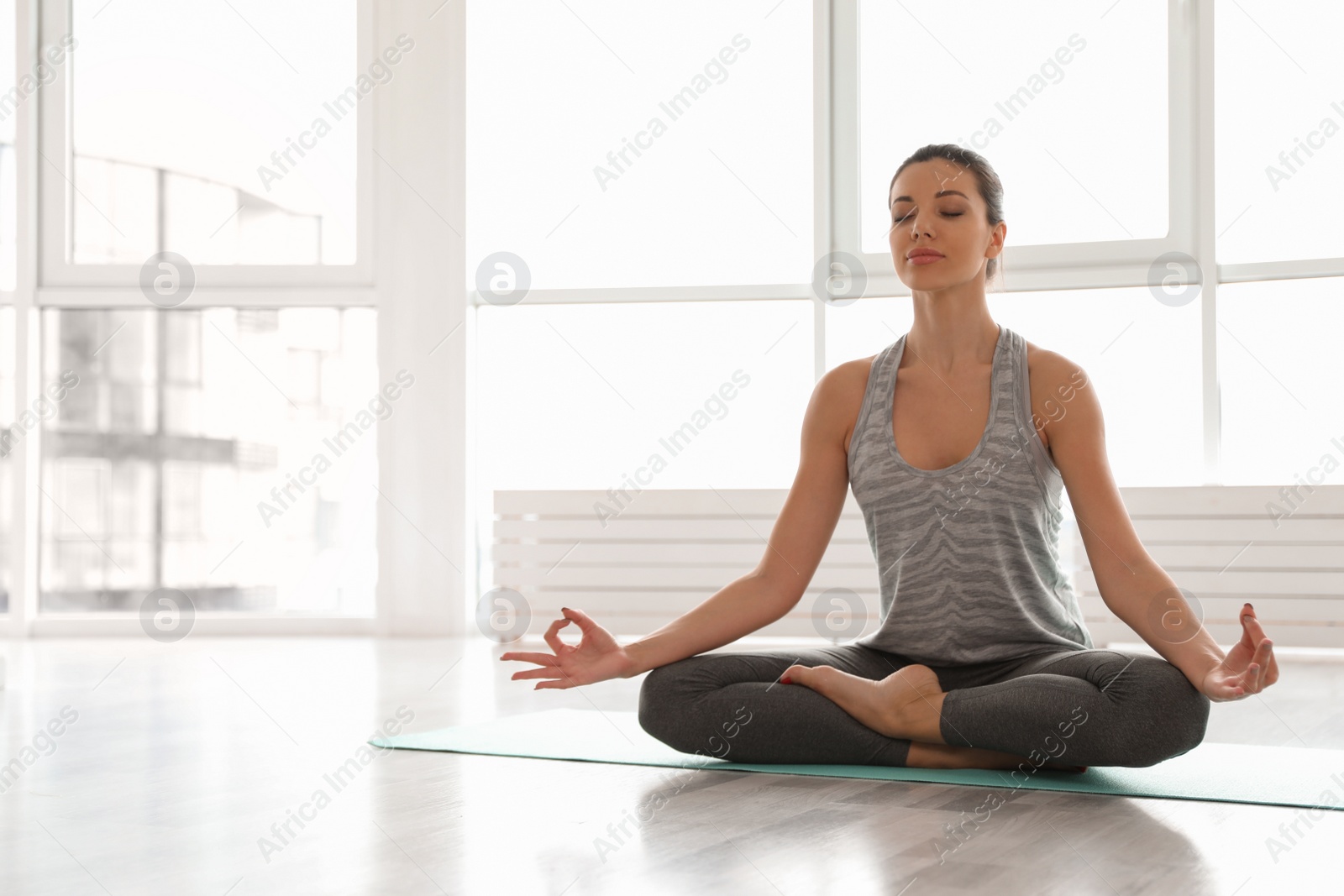 Photo of Young woman practicing yoga in studio. Accomplished pose (Siddhasana)