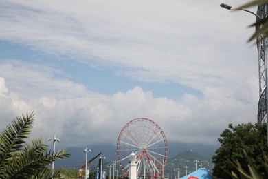 Photo of BATUMI, GEORGIA - JUNE 14, 2022: Beautiful landscape with Ferris wheel against cloudy sky