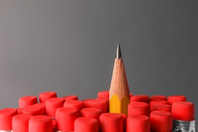Photo of Sharp graphite pencil among others with erasers on grey background, closeup. Space for text