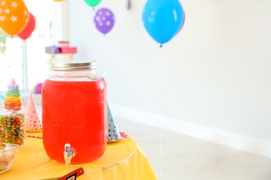 Photo of Drink dispenser with cold beverage on table at birthday party indoors