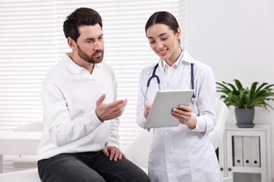 Doctor with tablet consulting patient during appointment in clinic