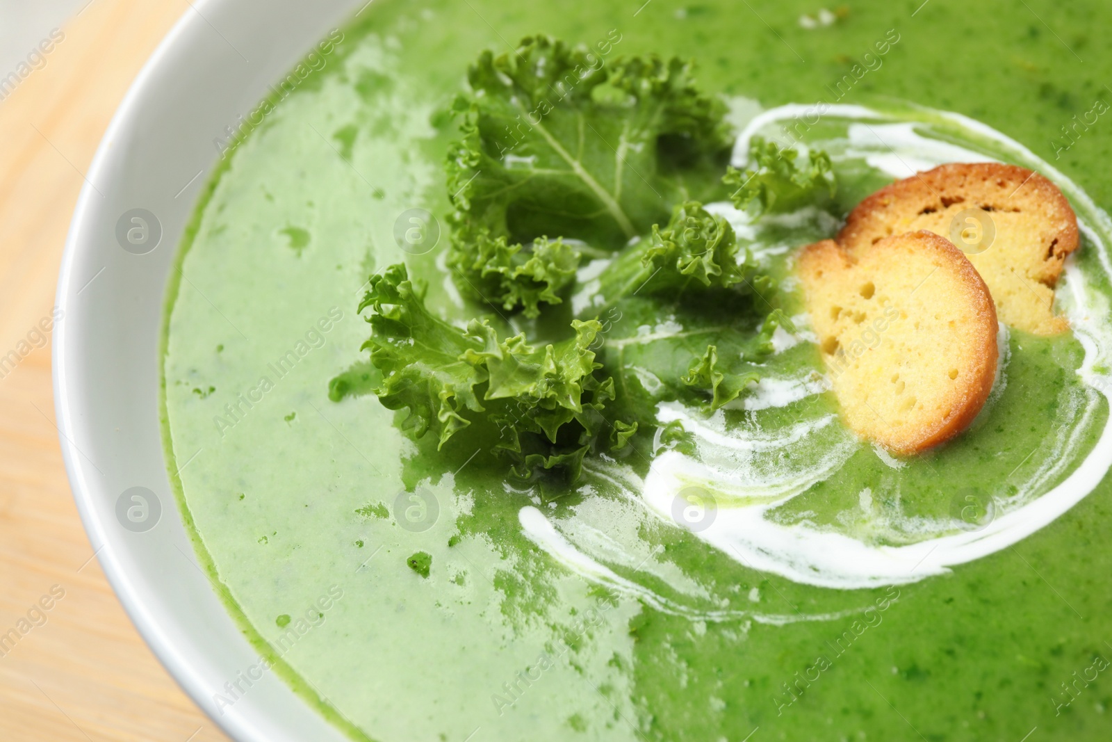 Photo of Tasty kale soup with croutons on table, closeup