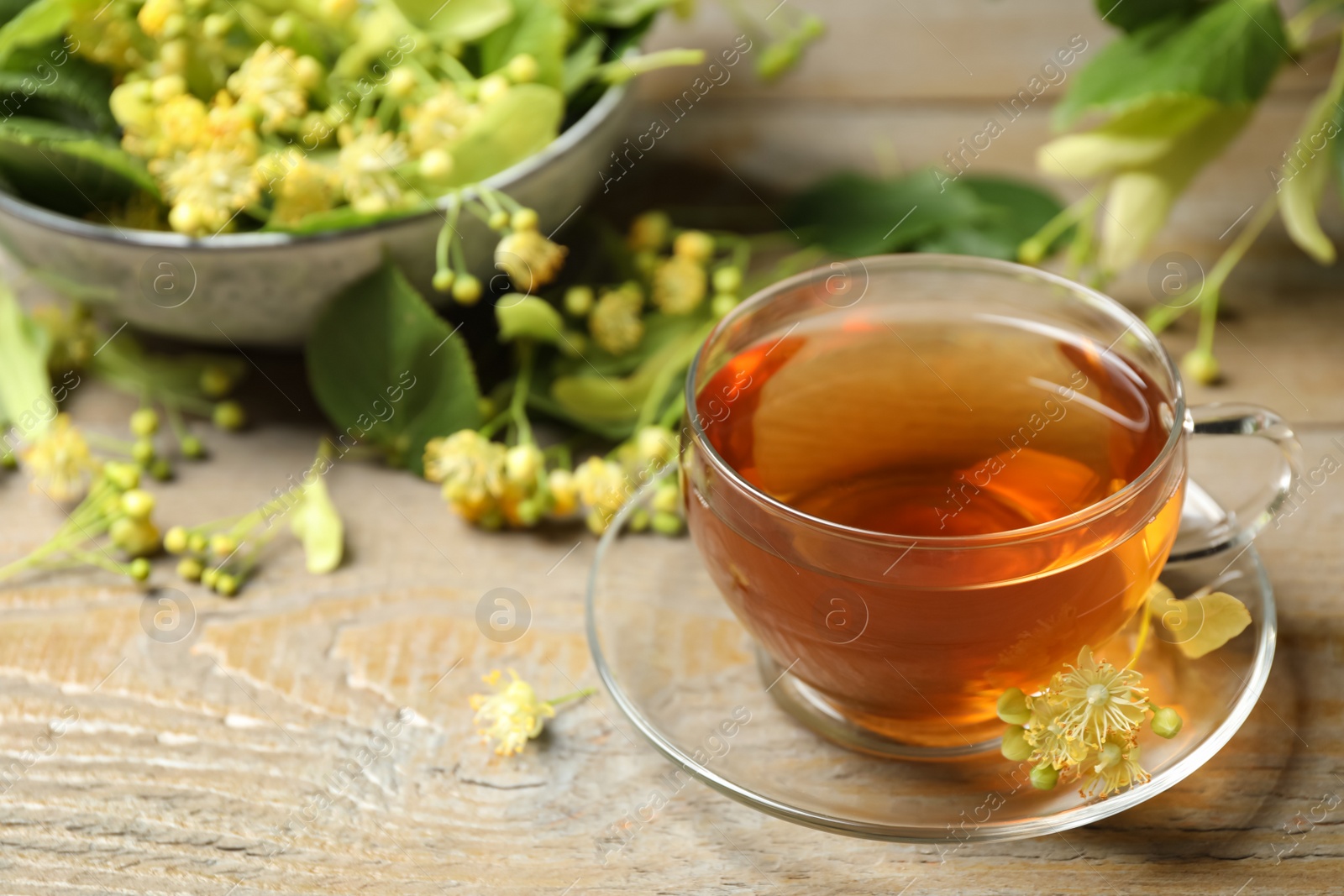 Photo of Cup of tea and linden blossom on wooden table. Space for text