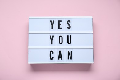 Photo of Lightbox with phrase Yes You Can on pale pink background, top view. Motivational quote