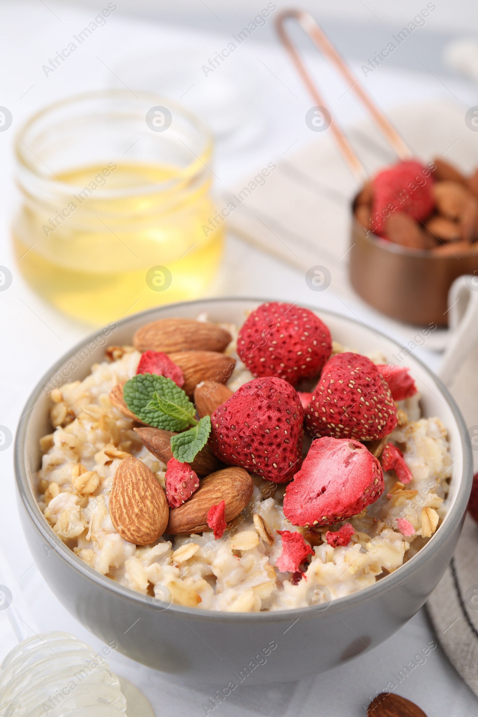 Photo of Delicious oatmeal with freeze dried strawberries, almonds and mint on table