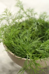 Bowl of fresh green dill with water drops on table, closeup