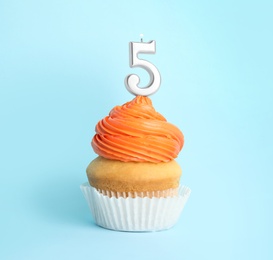 Birthday cupcake with number five candle on blue background