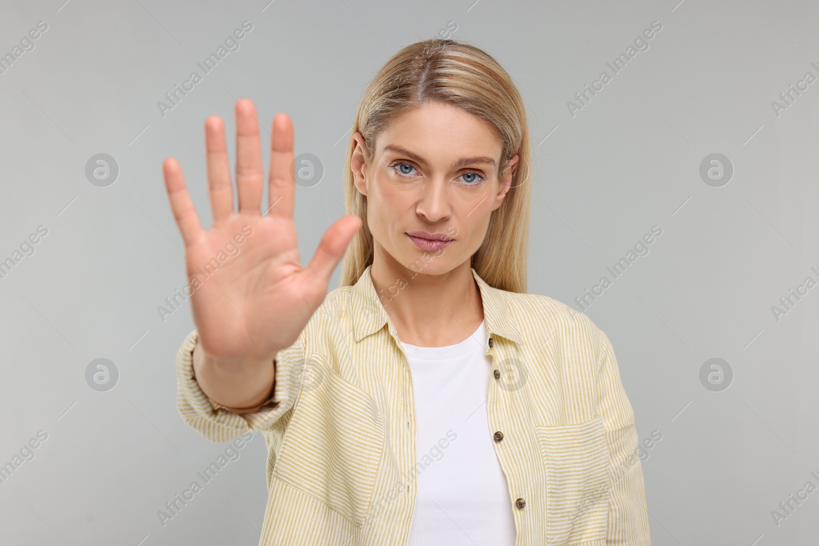 Photo of Woman showing stop gesture on grey background