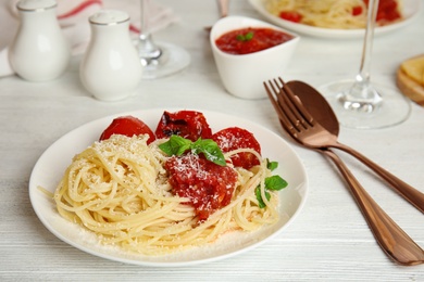 Tasty pasta with basil and tomato sauce on white wooden table