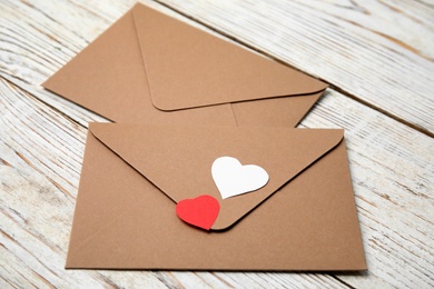 Envelopes and paper hearts on white wooden table, closeup. Love letters