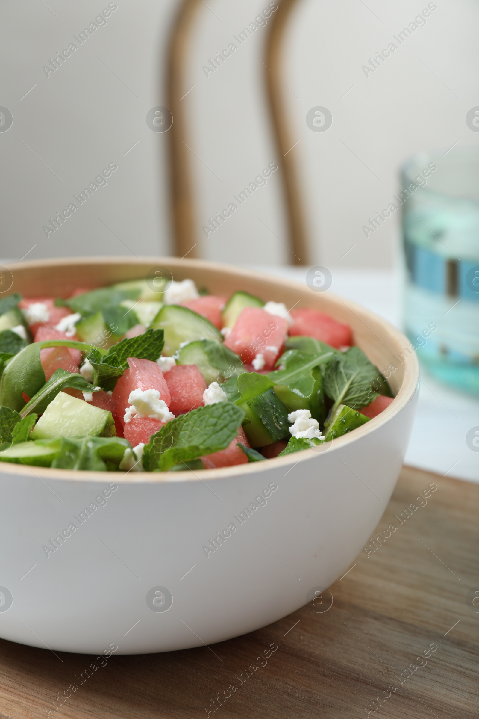 Photo of Delicious salad with watermelon, cucumber, arugula and feta cheese on wooden table, closeup