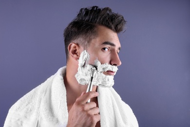 Photo of Handsome young man shaving on color background