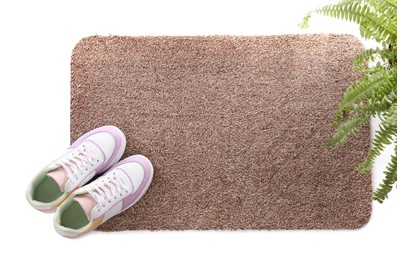 Stylish door mat with shoes and plant on white background, top view