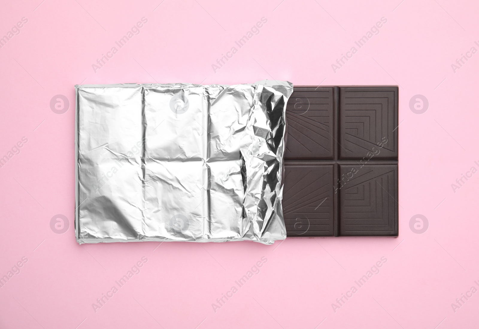 Photo of Tasty chocolate bar on pink background, top view