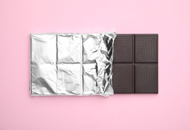 Photo of Tasty chocolate bar on pink background, top view