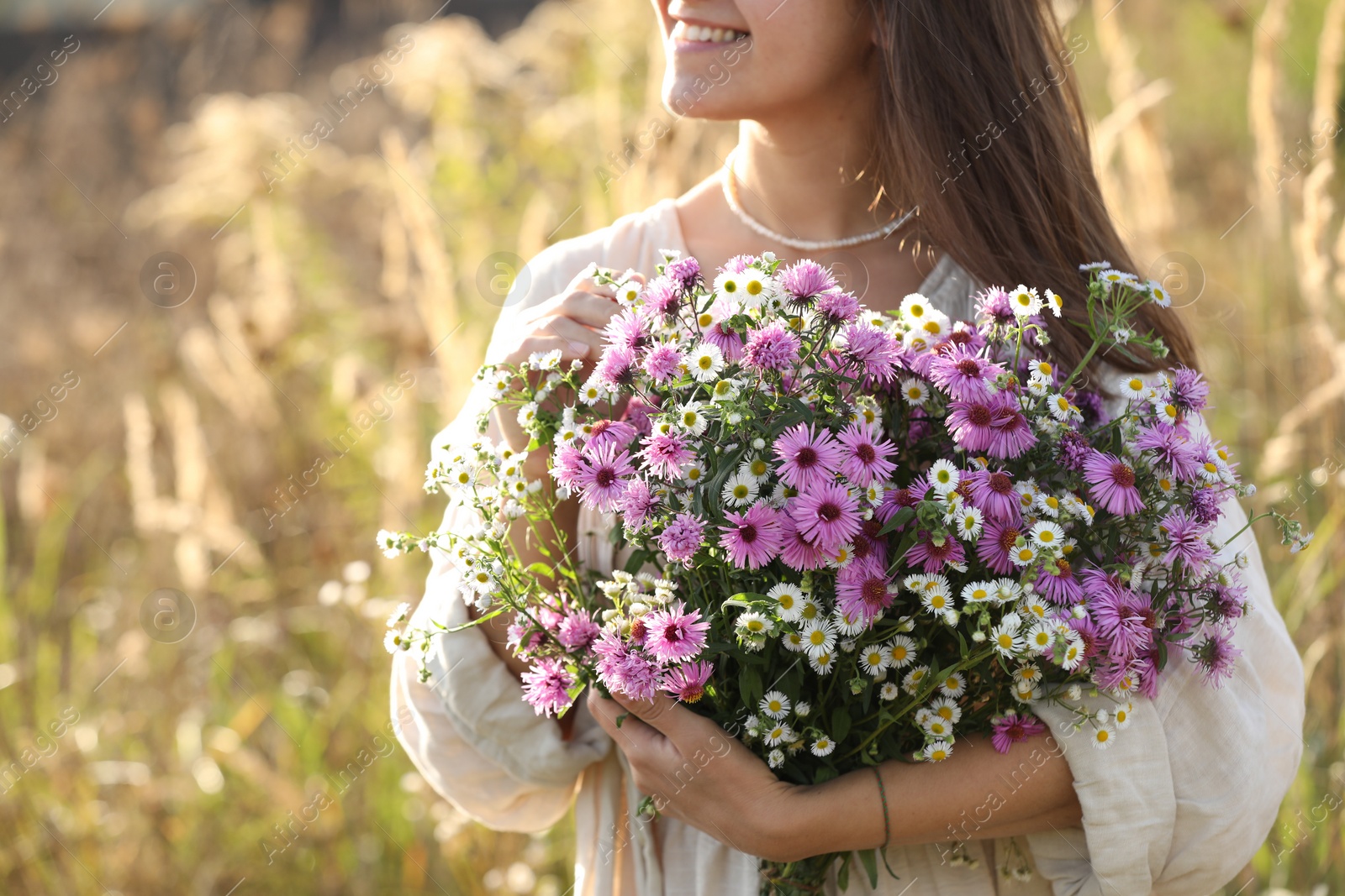 Photo of Woman holding bouquet of beautiful wild flowers outdoors, closeup. Space for text