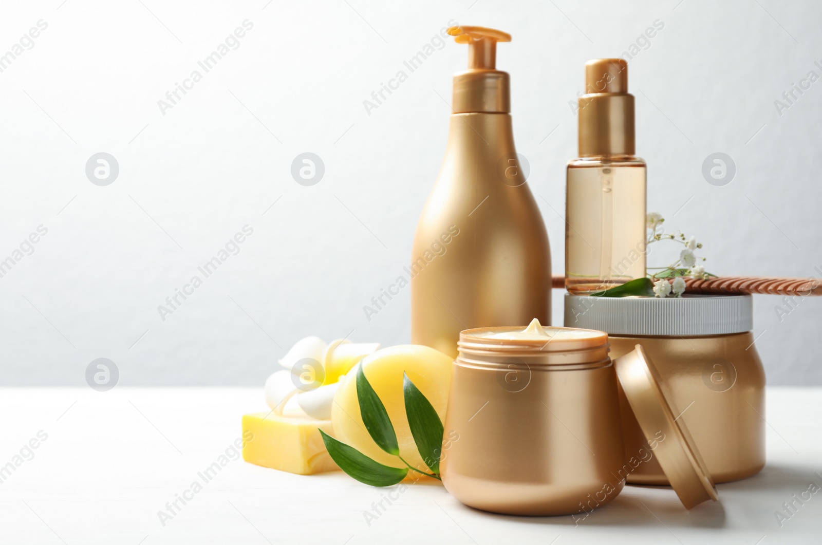 Photo of Set of hair cosmetic products and flowers on white wooden table. Space for text