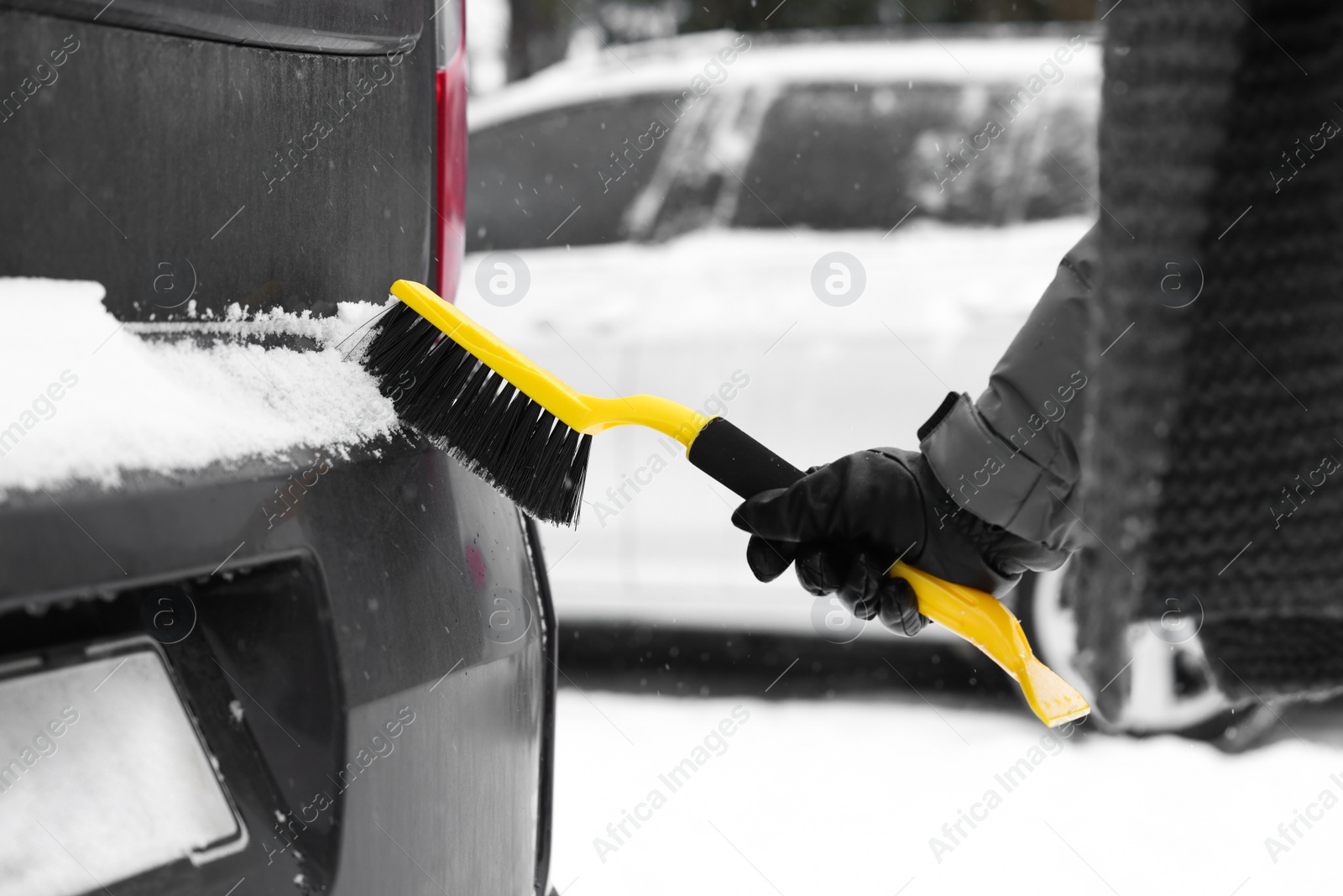 Photo of Man cleaning snow from car outdoors, closeup