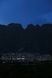 Photo of Picturesque view of beautiful city near mountains at night