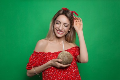 Photo of Young woman with fresh coconut on green background. Exotic fruit