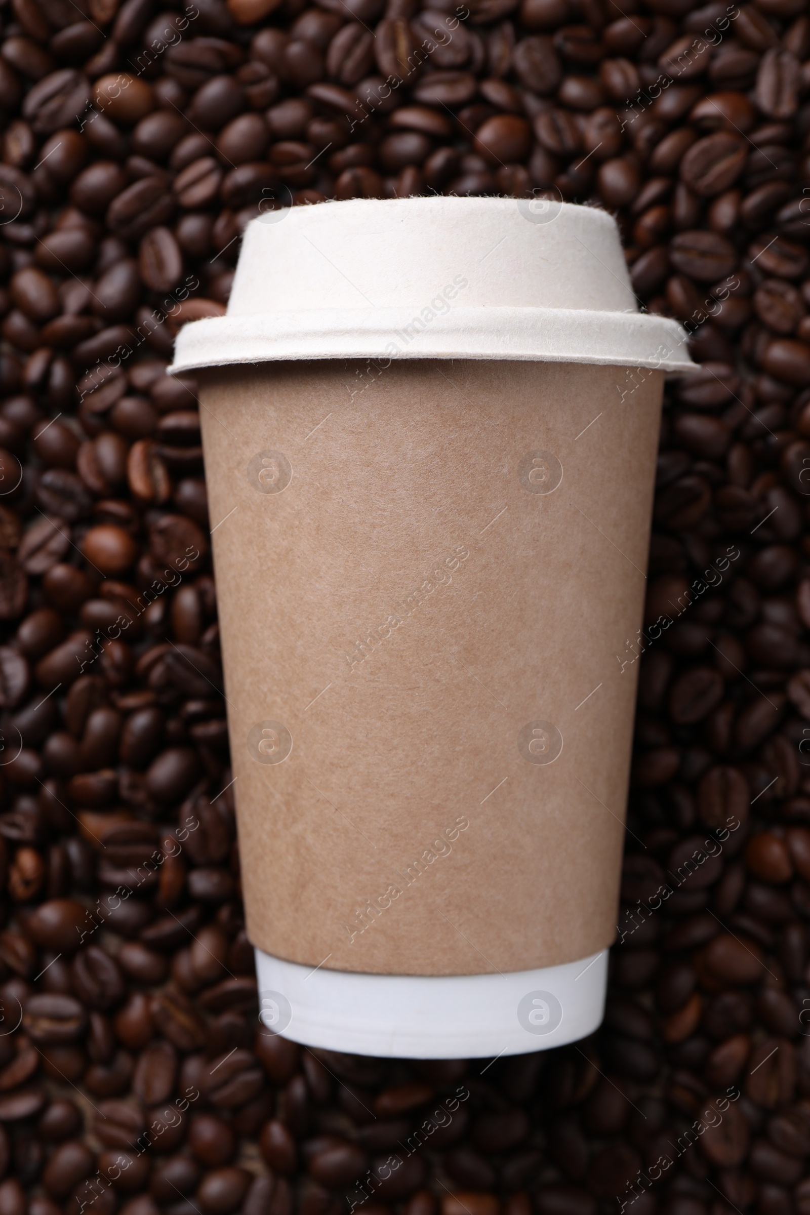 Photo of Coffee to go. Paper cup on roasted beans, top view