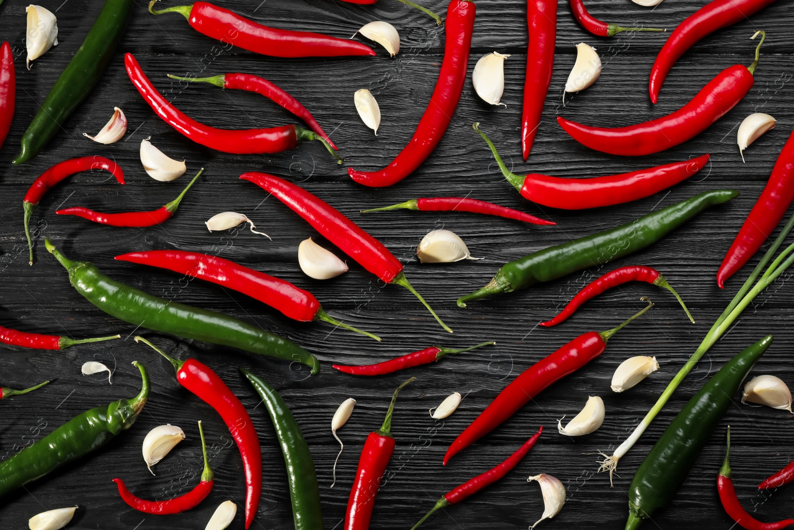Photo of Different chili peppers and garlic on black wooden table, flat lay
