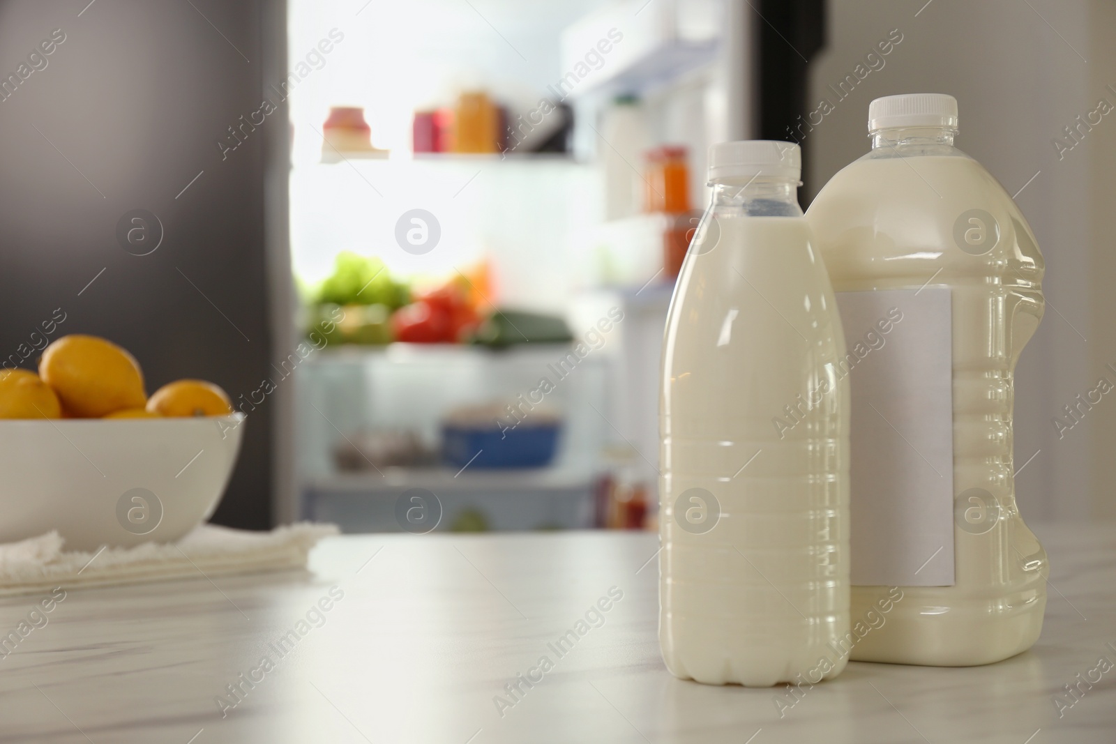 Photo of Gallon and bottle of milk on table in kitchen, space for text