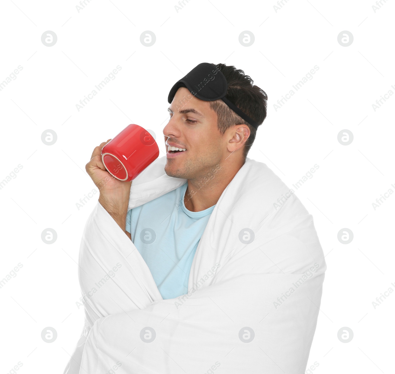 Photo of Man in sleeping mask wrapped with blanket holding cup on white background