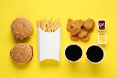 Photo of Different fast food on yellow background, flat lay
