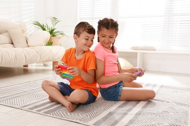 Children playing with pop it fidget toys on floor at home