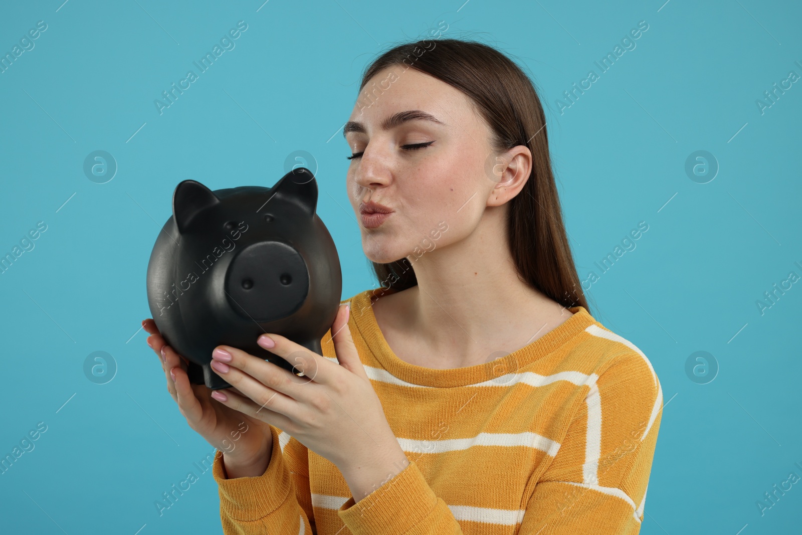 Photo of Woman with piggy bank on light blue background