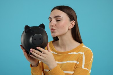 Woman with piggy bank on light blue background